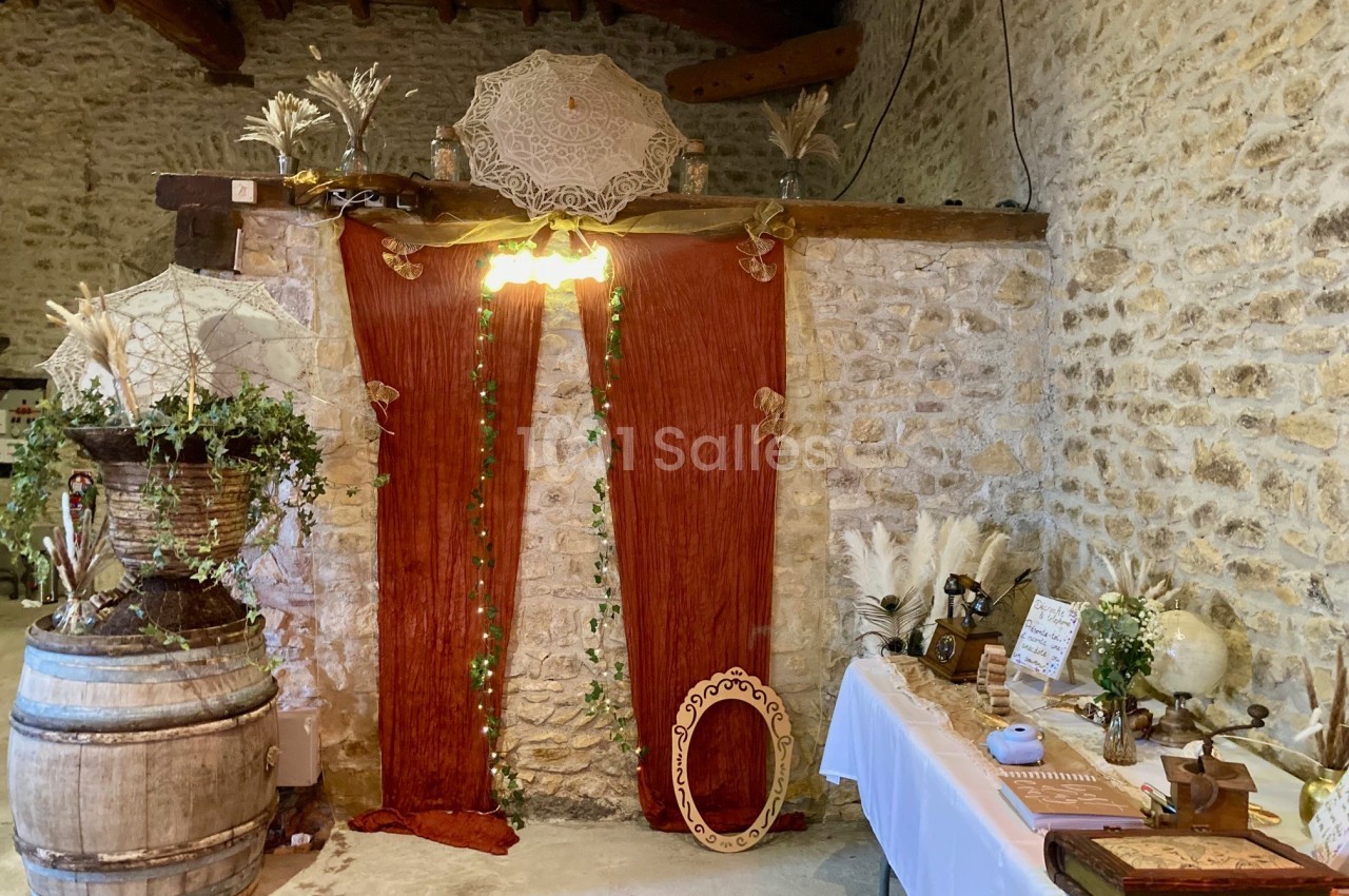 Décoration rustique avec rideaux rouges, guirlande lumineuse, objets vintage et plantes dans une pièce en pierre.