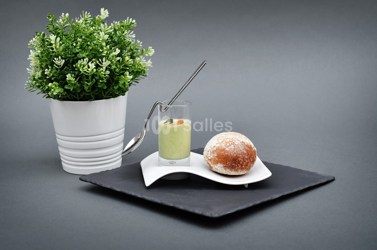 Plante verte en pot à côté d'une verrine de soupe verte avec une cuillère et un petit pain sur une assiette.