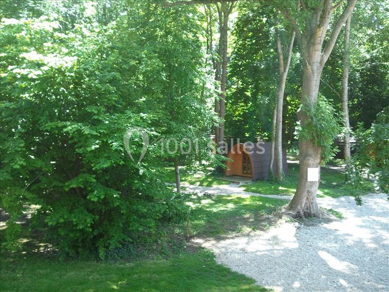 Un petit chalet en bois entouré d'arbres dans une clairière verdoyante avec un chemin de gravier.