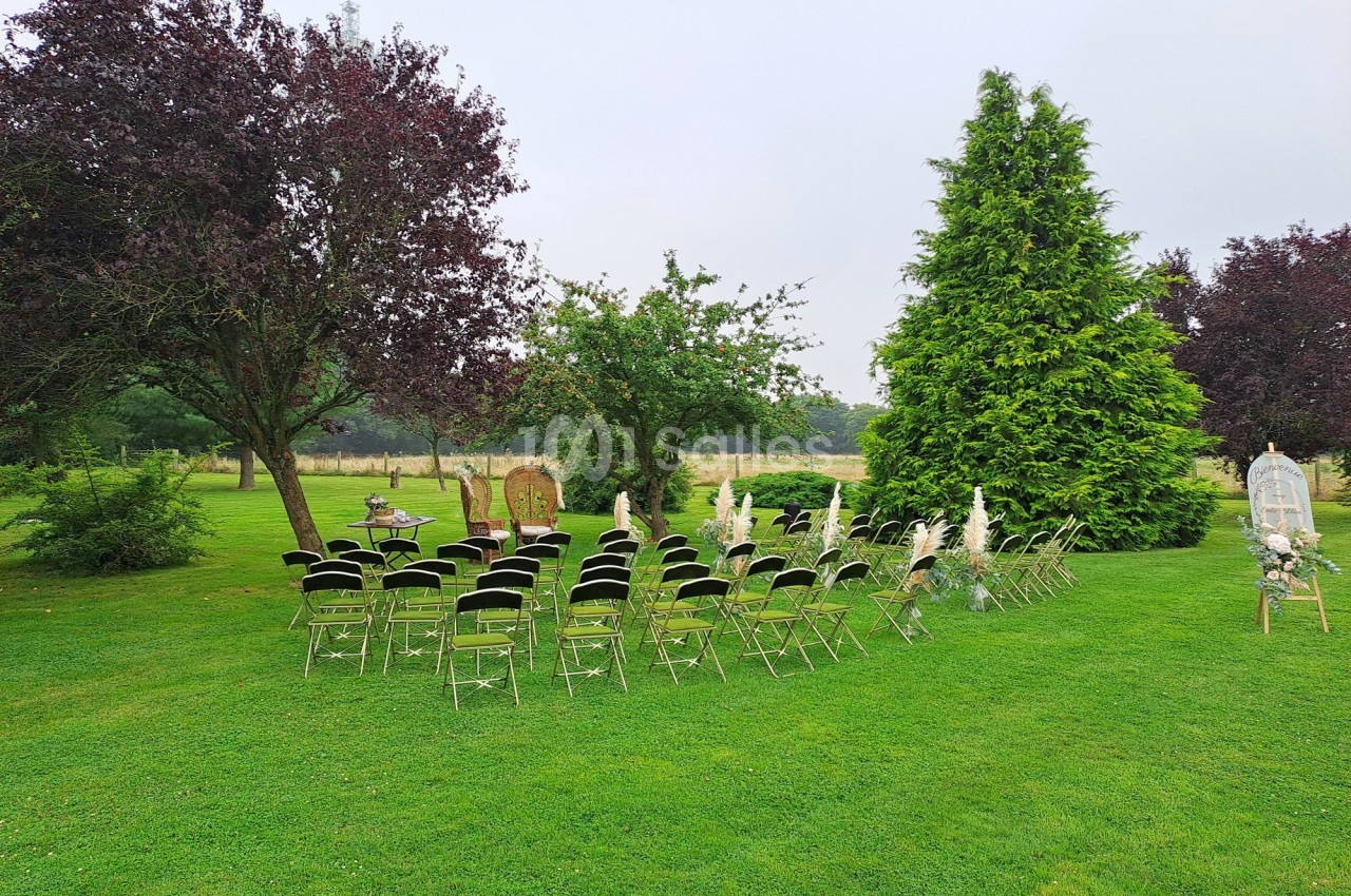 Chaises alignées en extérieur sur une pelouse, entourées d'arbres, préparées pour un événement en plein air.